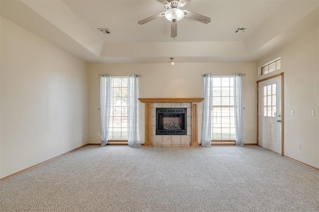 unfurnished living room featuring light colored carpet, a raised ceiling, and plenty of natural light