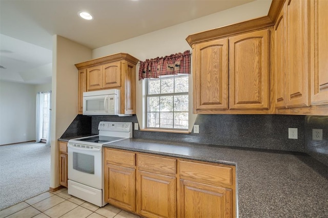 kitchen featuring backsplash, light tile patterned flooring, and white appliances