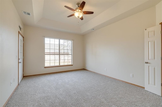 unfurnished bedroom featuring ceiling fan, light carpet, and a tray ceiling