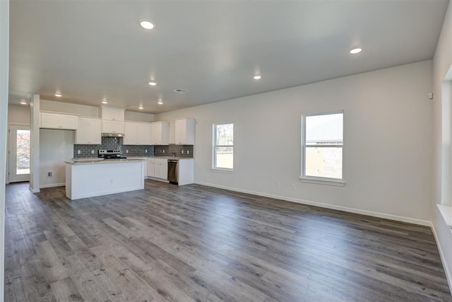 kitchen with a center island, stainless steel appliances, white cabinetry, and light hardwood / wood-style flooring