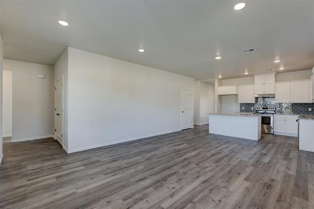 kitchen with light wood-type flooring, tasteful backsplash, stainless steel range with electric stovetop, a center island, and white cabinetry