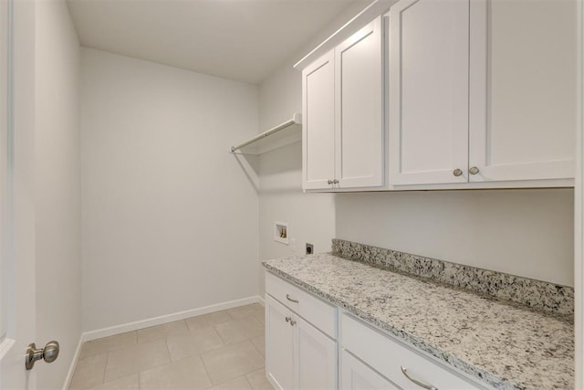 clothes washing area featuring hookup for an electric dryer, hookup for a washing machine, light tile patterned floors, and cabinets