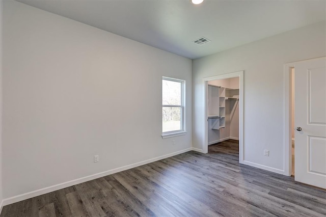 unfurnished bedroom with hardwood / wood-style floors, a spacious closet, and a closet