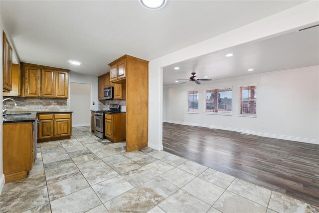 kitchen featuring backsplash, sink, ceiling fan, appliances with stainless steel finishes, and light hardwood / wood-style floors