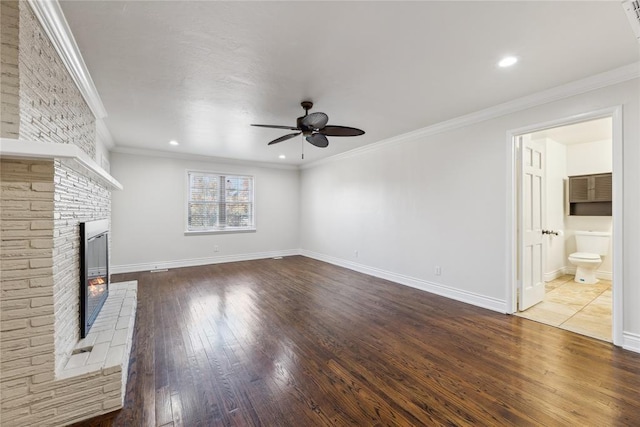 unfurnished living room with wood-type flooring, a brick fireplace, ceiling fan, and ornamental molding