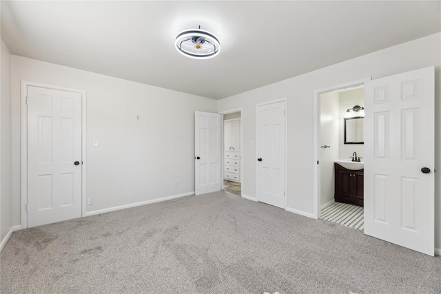 unfurnished bedroom featuring ensuite bath, sink, and light colored carpet