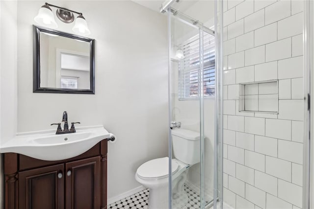 bathroom featuring vanity, a shower with shower door, and toilet