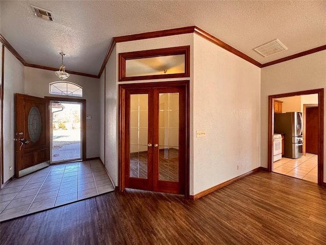 foyer with hardwood / wood-style flooring, crown molding, a textured ceiling, and french doors