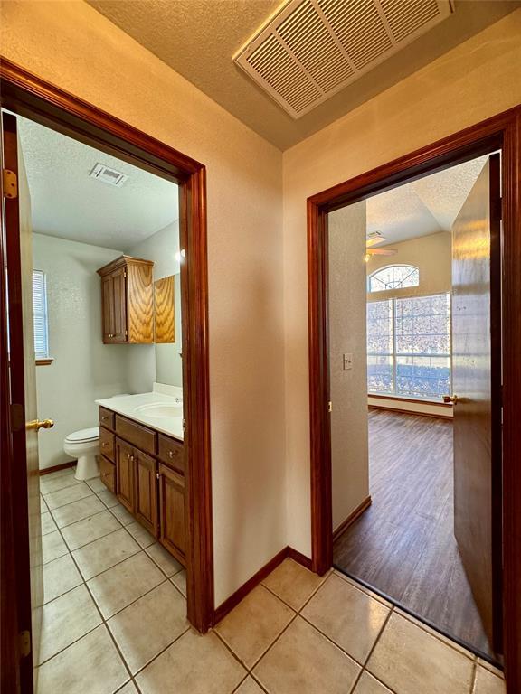 hall featuring a textured ceiling, light tile patterned floors, and sink