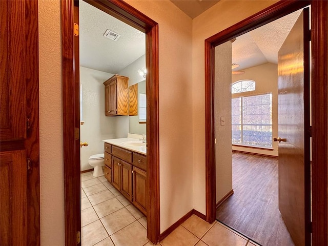 bathroom featuring hardwood / wood-style floors, vanity, lofted ceiling, toilet, and a textured ceiling