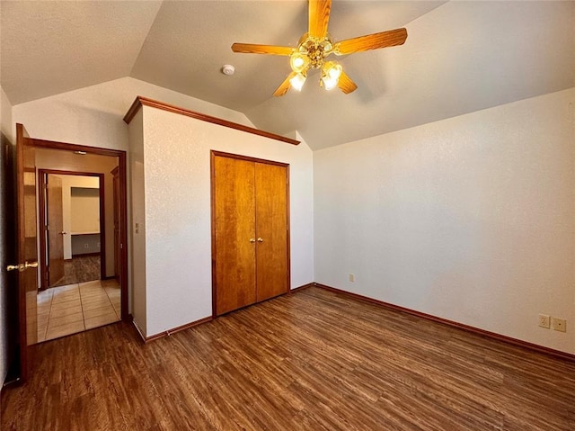 unfurnished bedroom featuring dark hardwood / wood-style flooring, vaulted ceiling, a closet, and ceiling fan