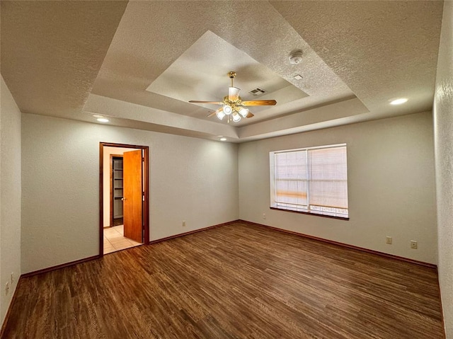 unfurnished room featuring hardwood / wood-style floors, ceiling fan, a raised ceiling, and a textured ceiling