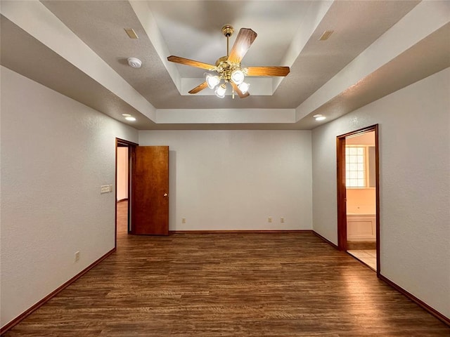 spare room featuring a raised ceiling, ceiling fan, and dark hardwood / wood-style flooring