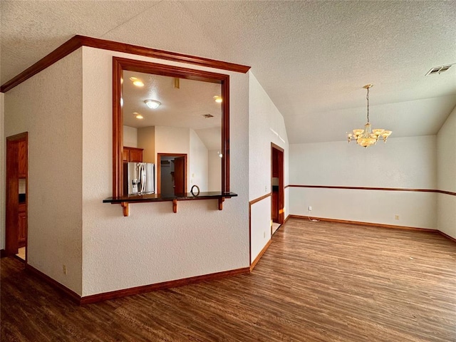 empty room with hardwood / wood-style flooring, a textured ceiling, and an inviting chandelier