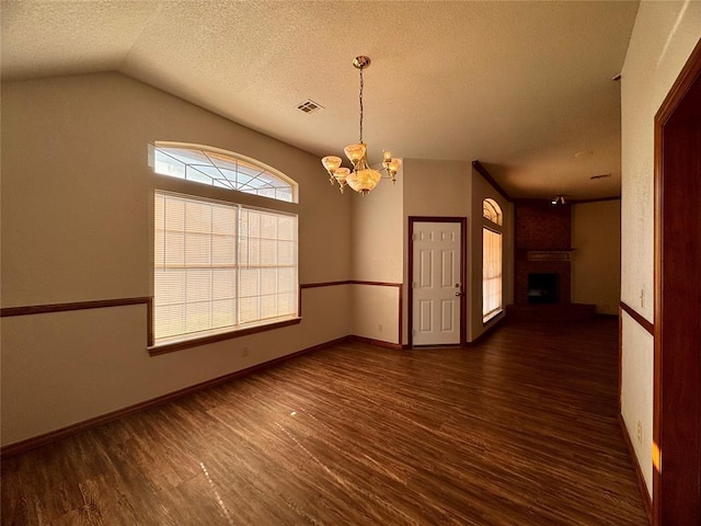 empty room featuring a textured ceiling, a fireplace, a chandelier, and dark hardwood / wood-style floors