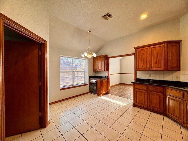 kitchen with backsplash, an inviting chandelier, wine cooler, vaulted ceiling, and light tile patterned floors