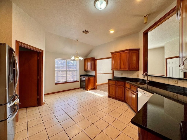 kitchen featuring dishwasher, sink, vaulted ceiling, a notable chandelier, and stainless steel refrigerator