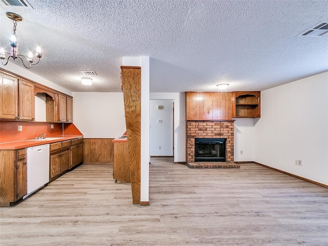 kitchen featuring white dishwasher, pendant lighting, a textured ceiling, and light wood-type flooring