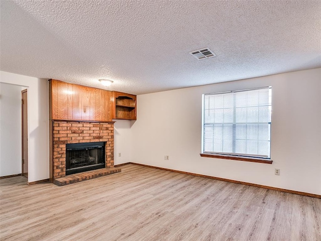 unfurnished living room with a fireplace, a textured ceiling, and light wood-type flooring