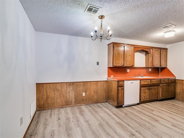 kitchen with white dishwasher, hanging light fixtures, a textured ceiling, and light hardwood / wood-style floors