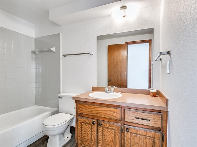 full bathroom featuring tiled shower / bath, hardwood / wood-style flooring, vanity, and toilet