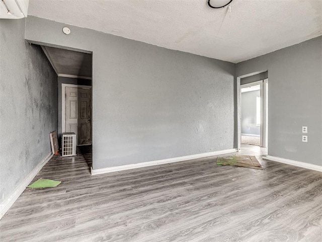 unfurnished room with a textured ceiling and light wood-type flooring