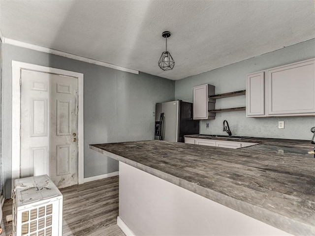 kitchen with sink, stainless steel fridge, hanging light fixtures, white cabinets, and dark hardwood / wood-style flooring