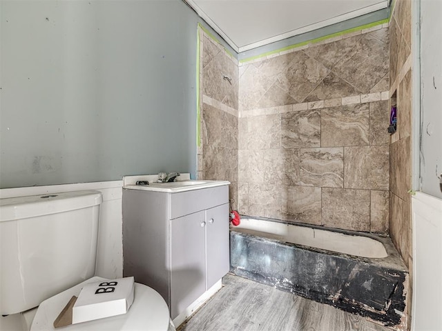 full bathroom with vanity, tiled shower / bath, hardwood / wood-style floors, and toilet