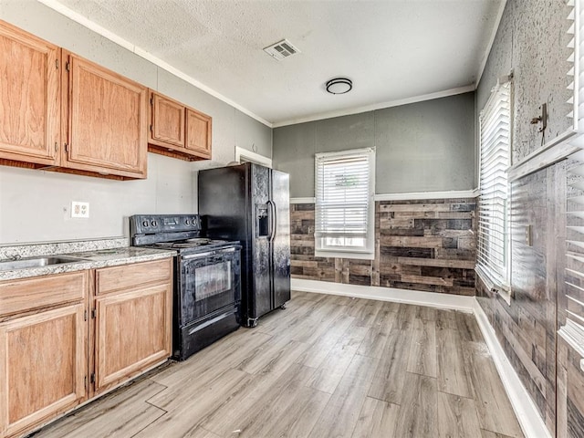 kitchen with light hardwood / wood-style flooring, ornamental molding, black appliances, a textured ceiling, and wood walls