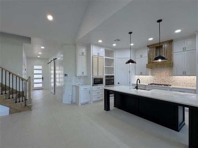 kitchen with stainless steel appliances, white cabinetry, a barn door, and sink