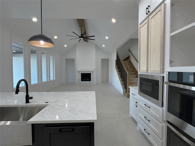 kitchen featuring pendant lighting, built in microwave, white cabinetry, a high end fireplace, and light stone counters