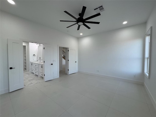 unfurnished bedroom featuring a walk in closet, ceiling fan, and ensuite bathroom