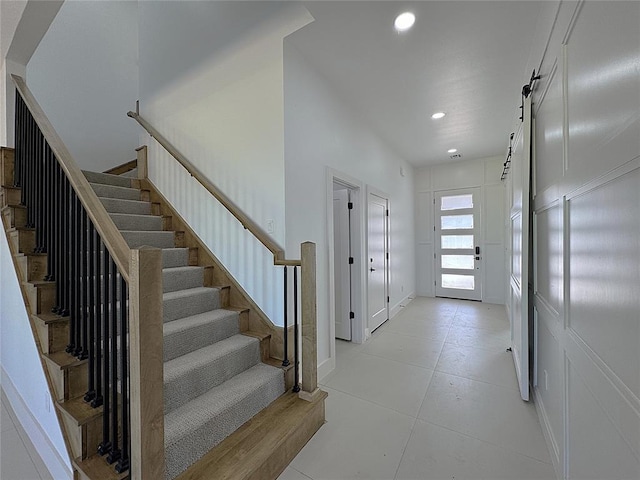 interior space featuring a decorative wall, recessed lighting, stairs, and a barn door