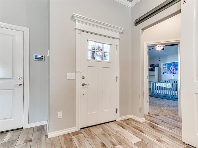 entryway with light hardwood / wood-style floors and crown molding