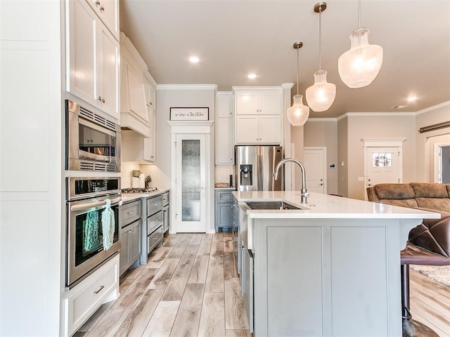 kitchen with a breakfast bar, white cabinetry, hanging light fixtures, and stainless steel appliances