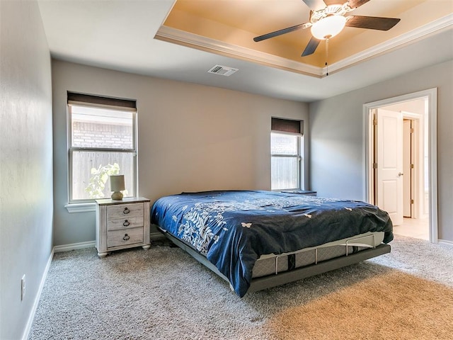 carpeted bedroom with a raised ceiling, multiple windows, and ceiling fan