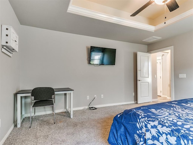 carpeted bedroom with a tray ceiling and ceiling fan