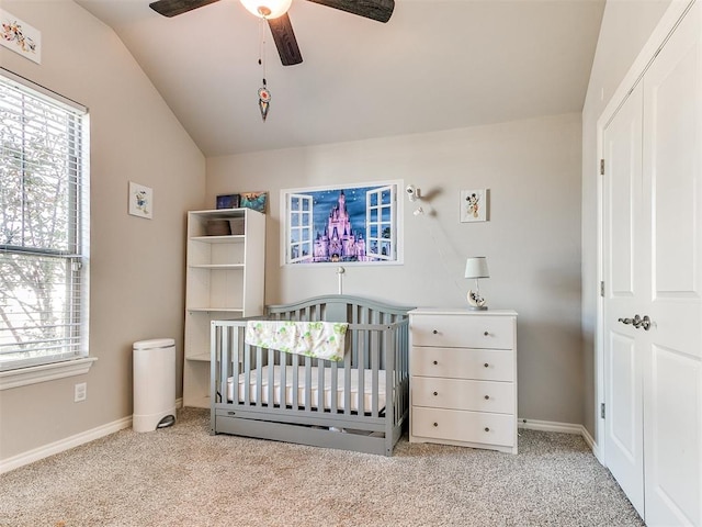 carpeted bedroom featuring ceiling fan, a nursery area, and vaulted ceiling