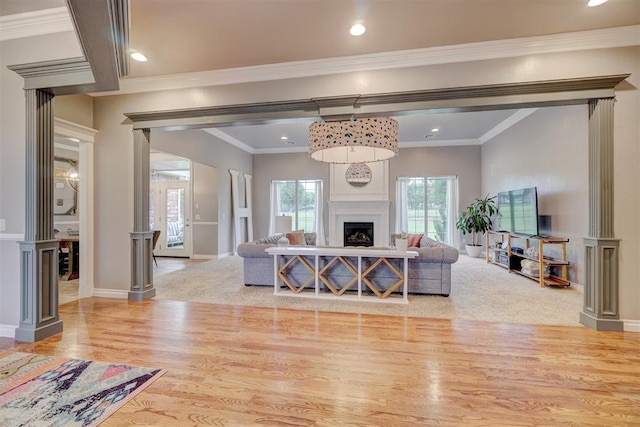 living room featuring decorative columns, crown molding, and light hardwood / wood-style floors