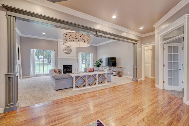 living room featuring a fireplace, light hardwood / wood-style flooring, plenty of natural light, and crown molding