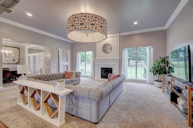 carpeted living room featuring a large fireplace, plenty of natural light, ornamental molding, and a notable chandelier