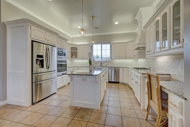 kitchen with light stone counters, decorative light fixtures, decorative backsplash, a center island with sink, and appliances with stainless steel finishes