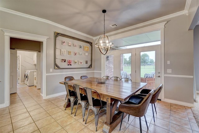 dining area with separate washer and dryer, crown molding, light tile patterned flooring, and a notable chandelier