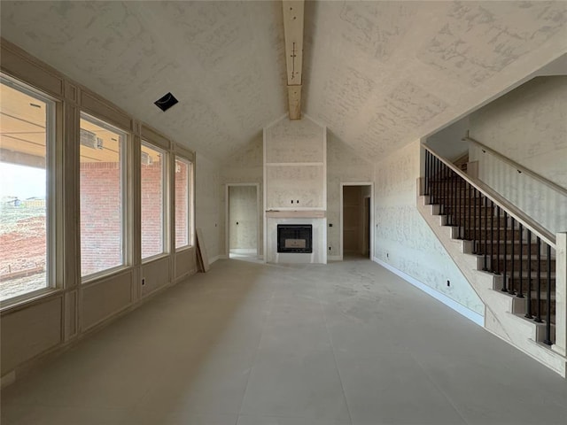 unfurnished living room with a wealth of natural light, a large fireplace, and beamed ceiling