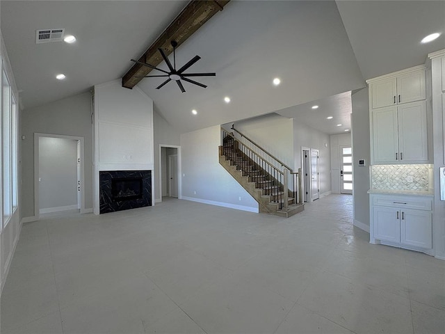 unfurnished living room with visible vents, beam ceiling, a ceiling fan, stairway, and a fireplace