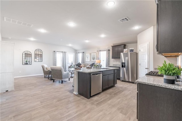 kitchen featuring sink, light hardwood / wood-style flooring, appliances with stainless steel finishes, a center island, and light stone counters