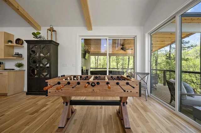 playroom featuring ceiling fan, light hardwood / wood-style flooring, and lofted ceiling with beams