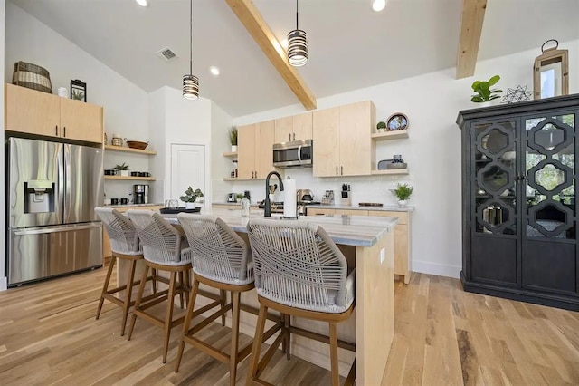 kitchen with beam ceiling, hanging light fixtures, light hardwood / wood-style floors, light brown cabinetry, and appliances with stainless steel finishes