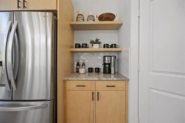 bar featuring light brown cabinetry, backsplash, and stainless steel refrigerator