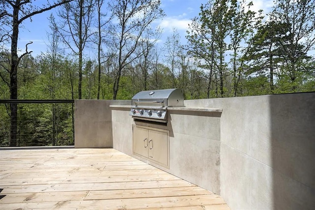 view of patio / terrace featuring grilling area, a wooden deck, and an outdoor kitchen